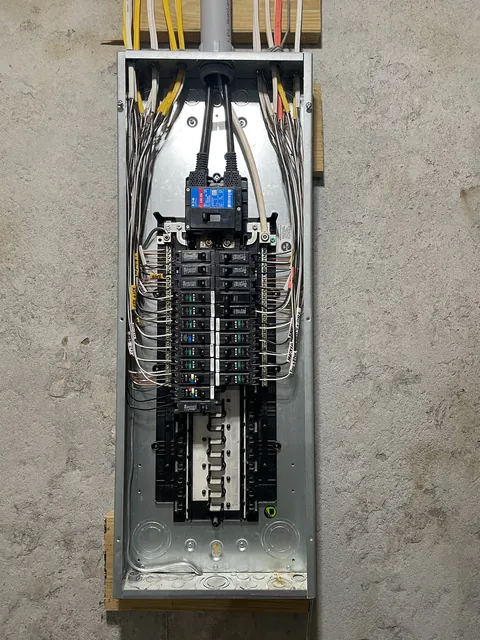 A 200 amp electrical panel with the cover open and new breakers installed and labeled.