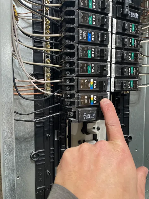 Electrician pointing to a breaker inside a newly installed electrical panel