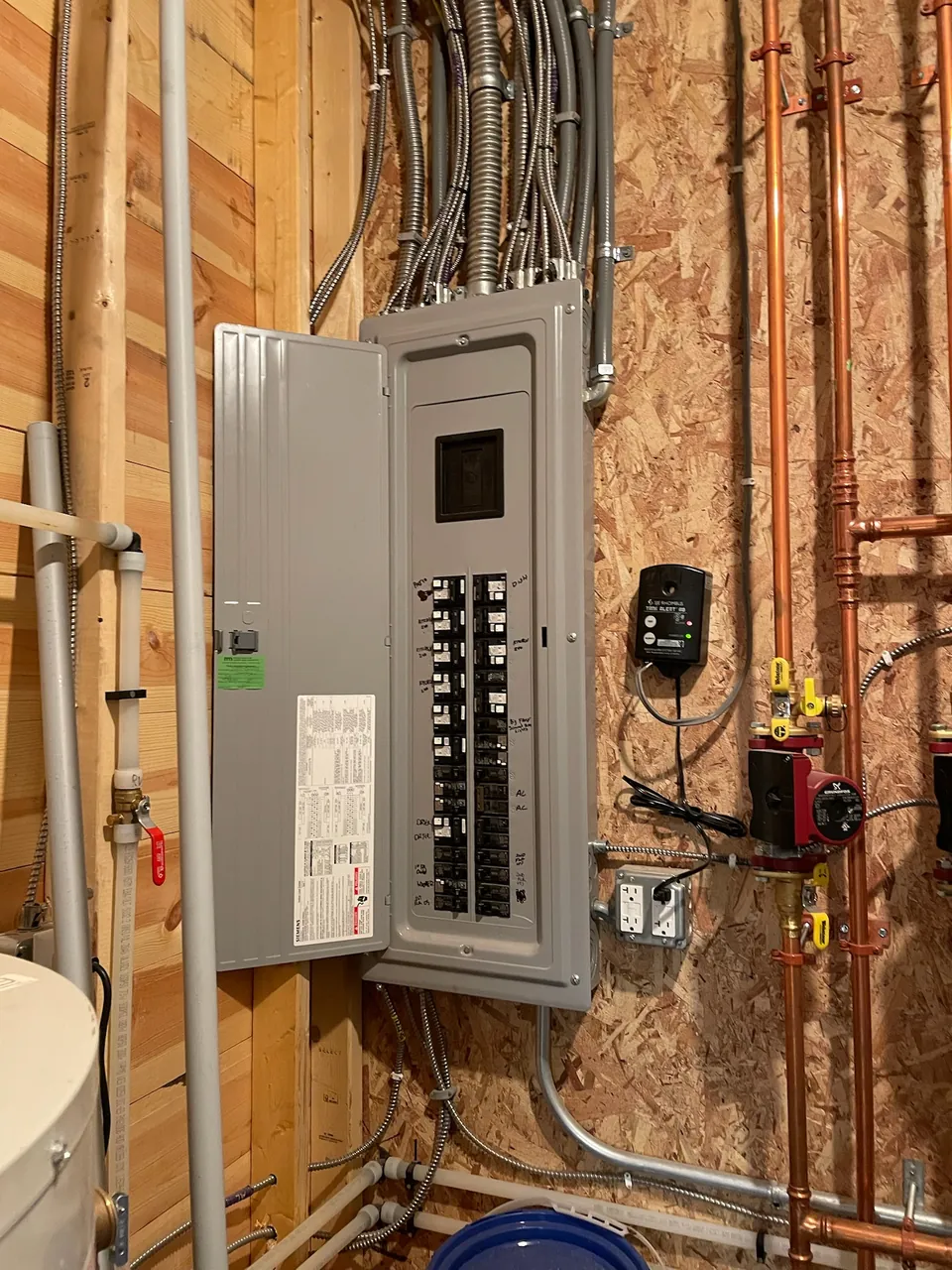 New electrical panel with conduit runs on a wall during construction