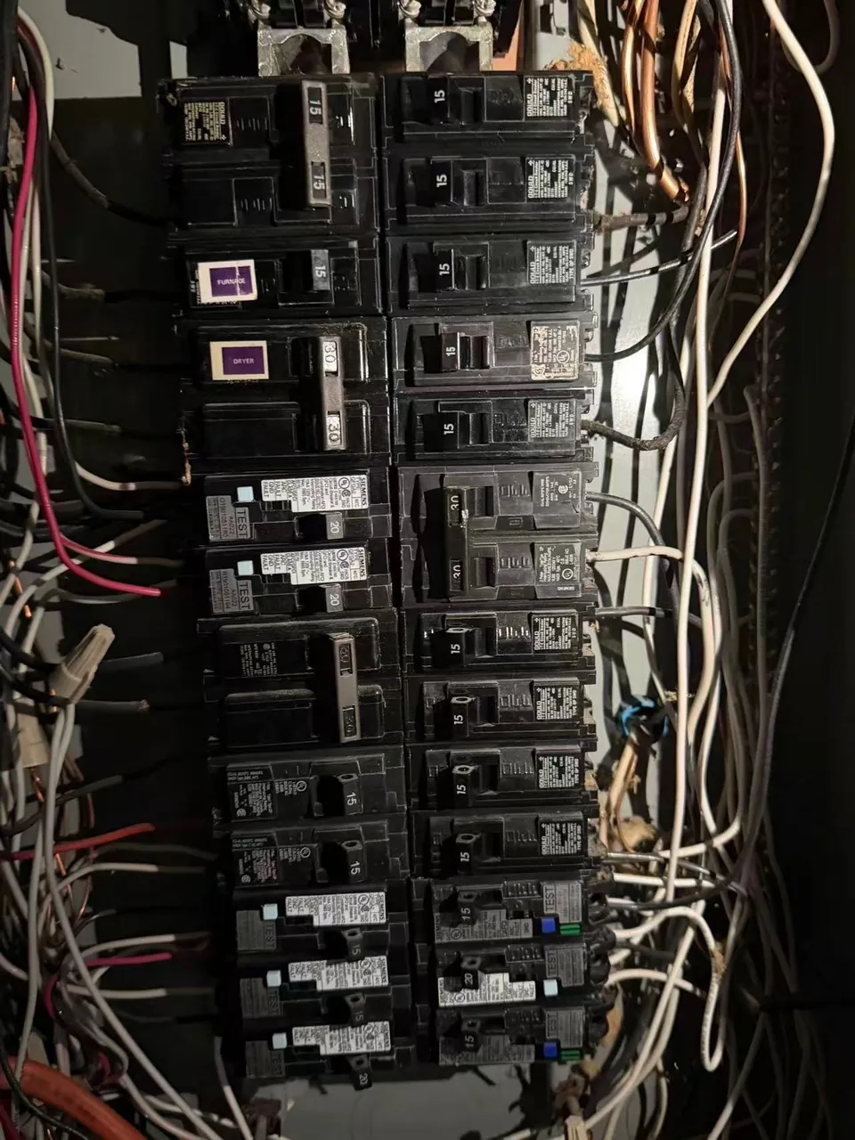 Old crowded electrical panel with unlabeled breakers before replacement